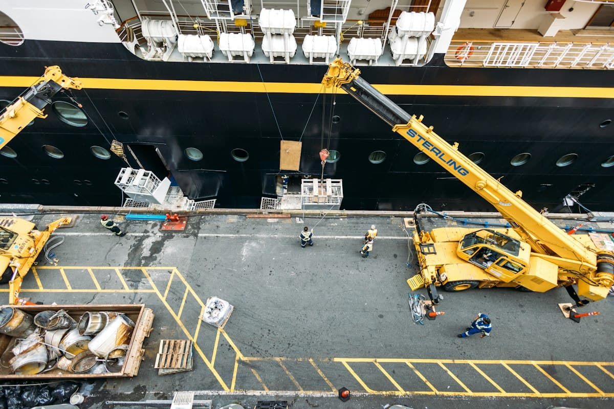 Cranes and workers on a ship deck at a shipyard