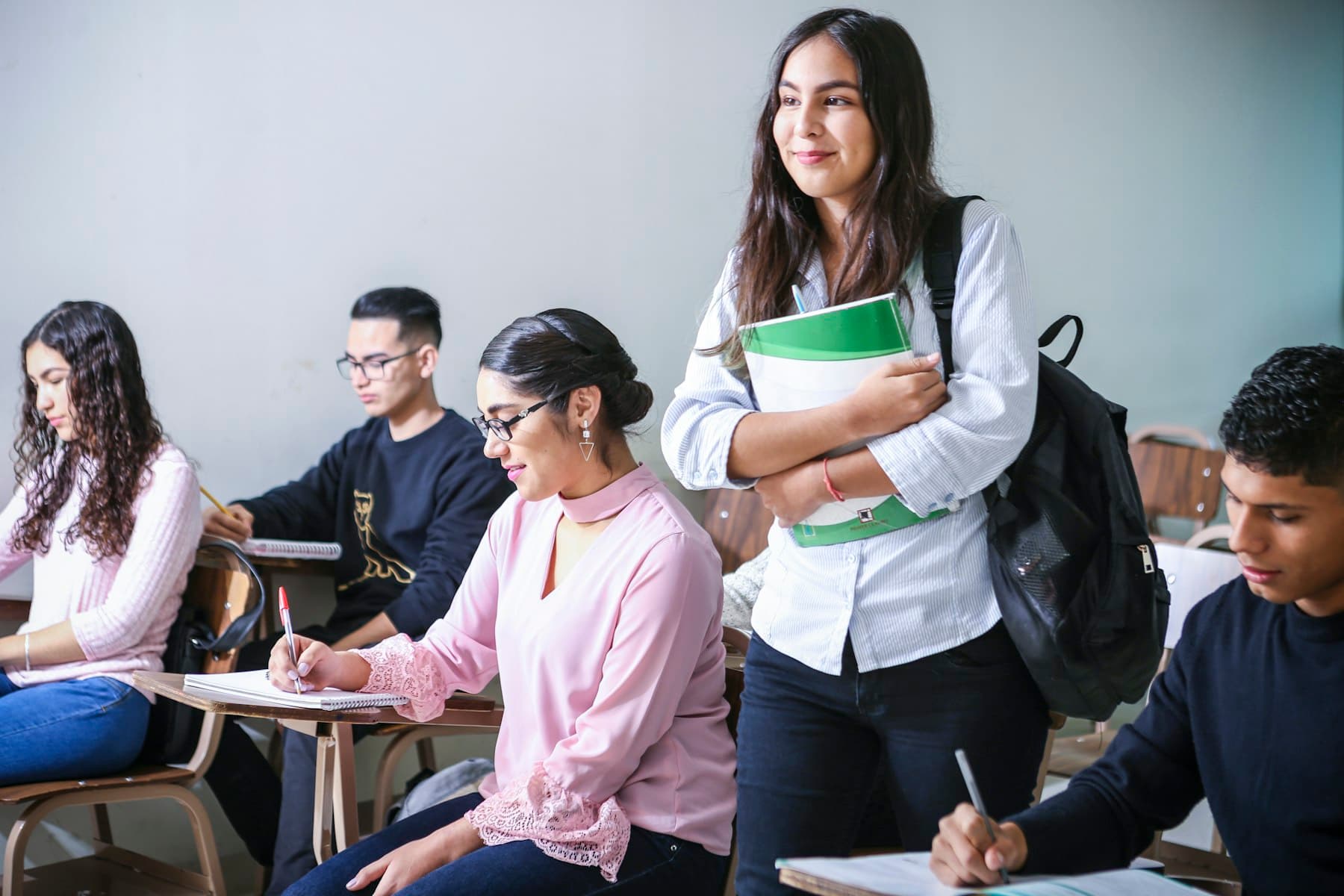 A smiling student holding books in a classroom