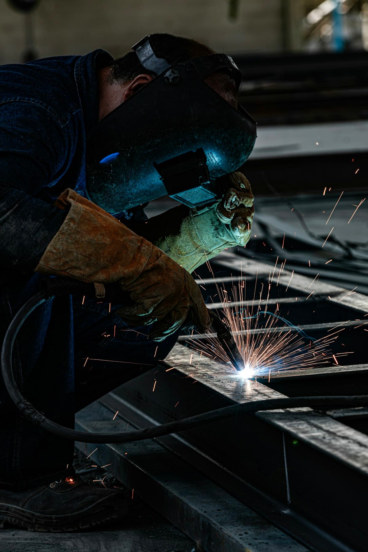 A welder joining steel parts, with sparks flying