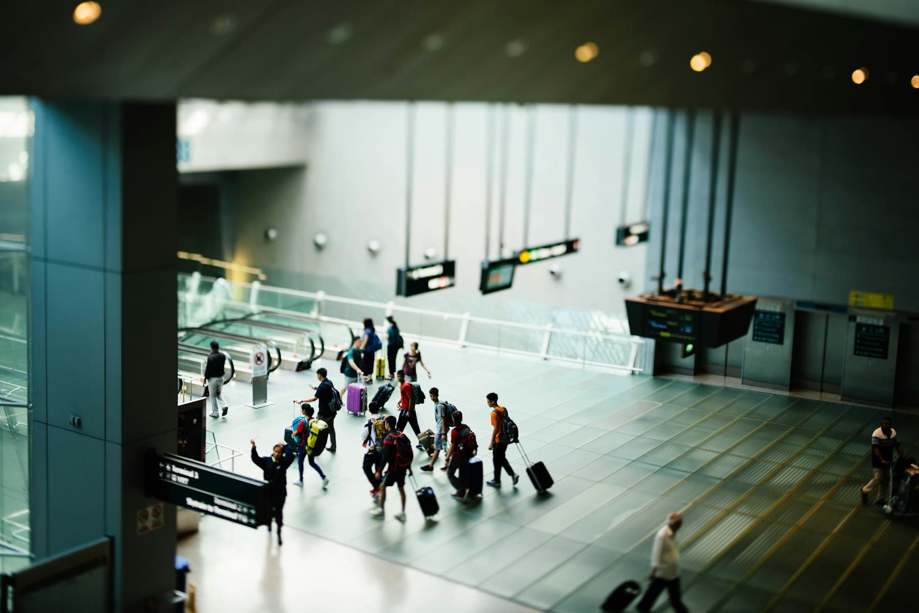 Travellers with luggage walking through a bright airport terminal